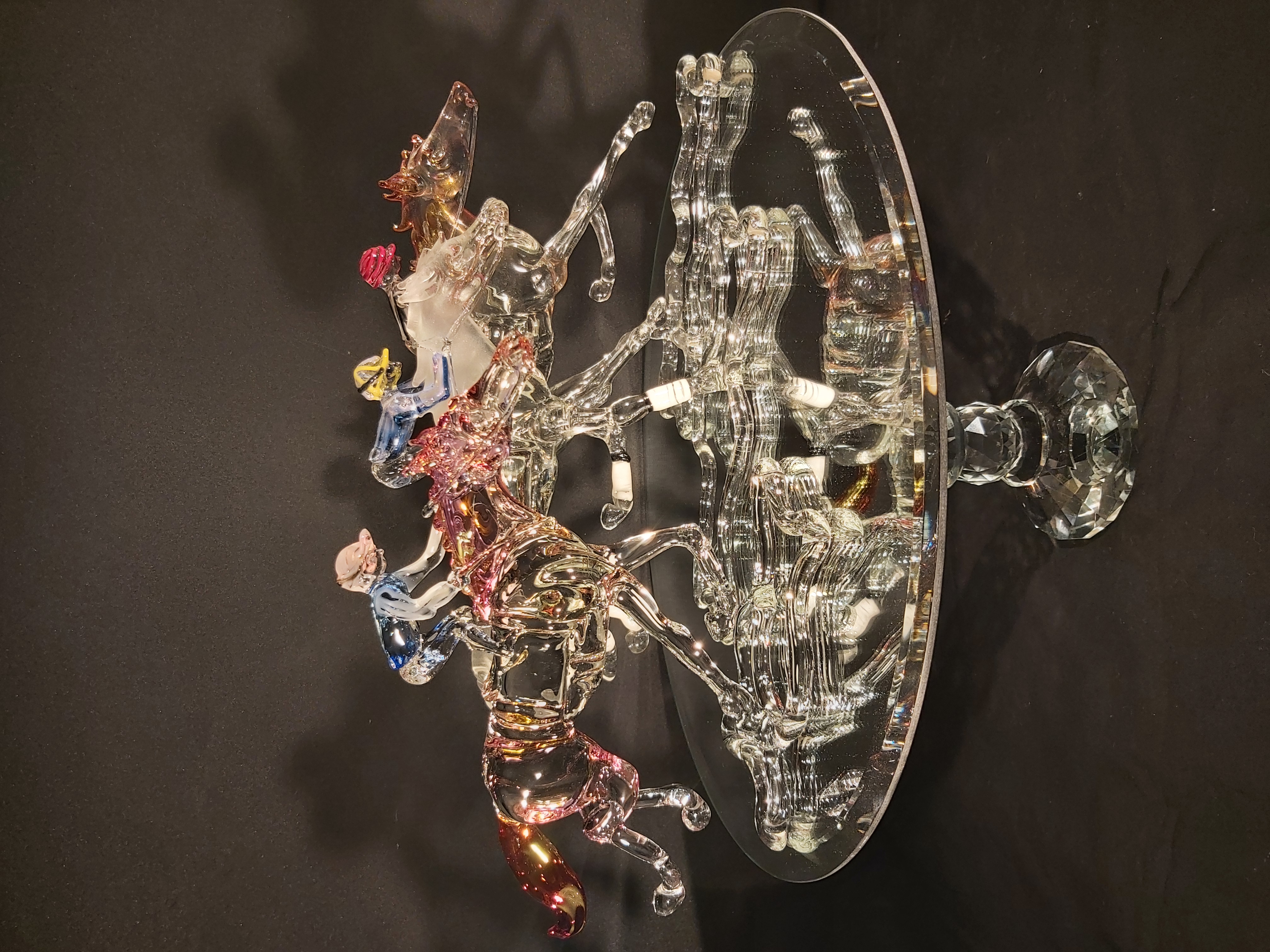 Three glass racehorses on a mirrored display stand